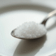 Cuillère en métal brillant avec sucre blanc fin en gros plan
