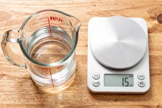 Verre doseur et balance de cuisine sur un plan de travail en bois